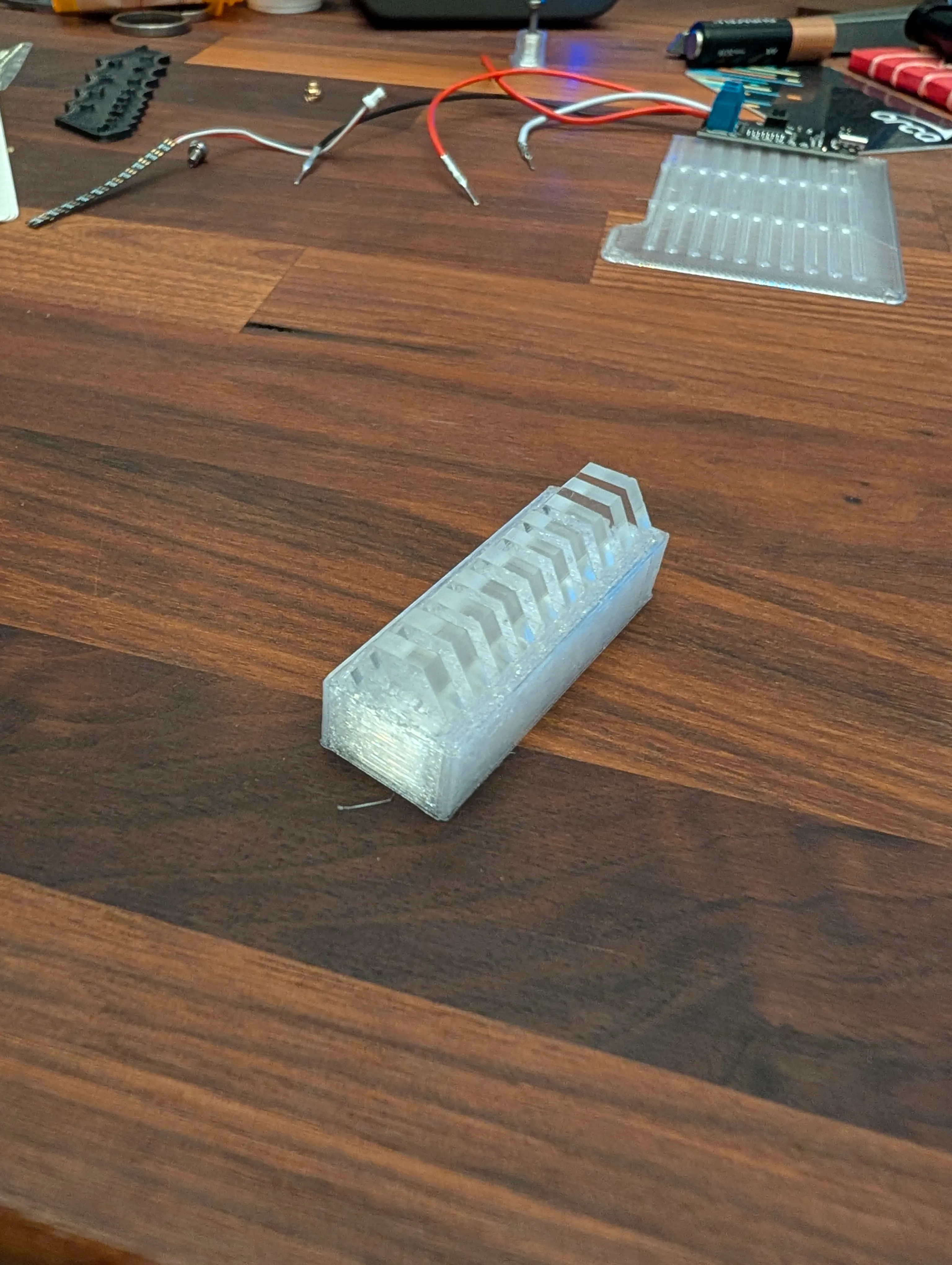 An early clear 3D-printed shell prototype on the workbench next to loose electronics